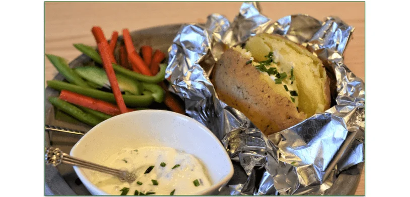 Baked potato with a bowl of sauce and pepper strips