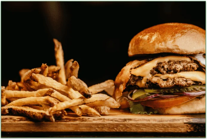 A burger and fries on a wooden serving dish.