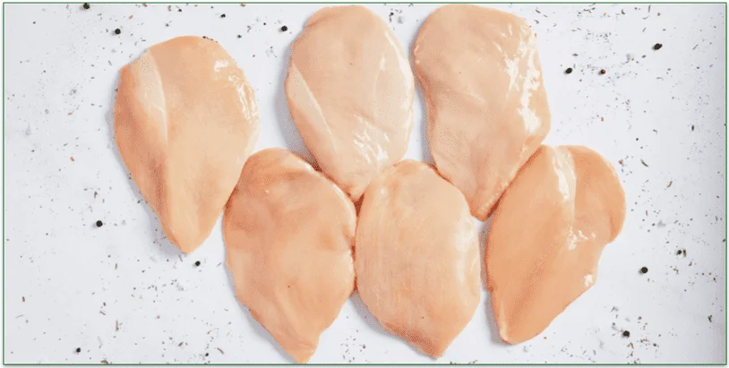 six raw chicken breasts on a marble table