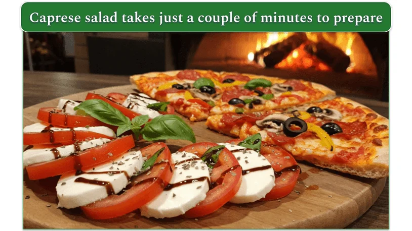 Caprese salad beside a few slices of pizza on a circular wooden serving tray.