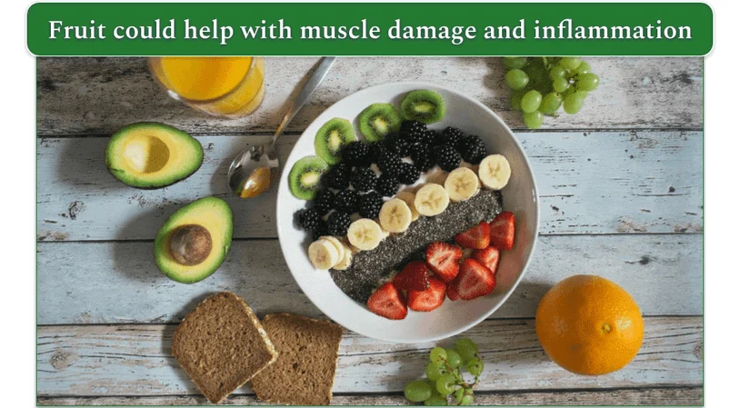 The image shows cut kiwi, bananas, strawberries, and other fruits on the plate while avocado, orange, and grapes lay next to it.