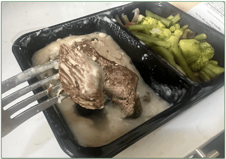 Diet-to-Go's Asian Steak dish in a microwaveable tray with a piece of steak lifted on a fork