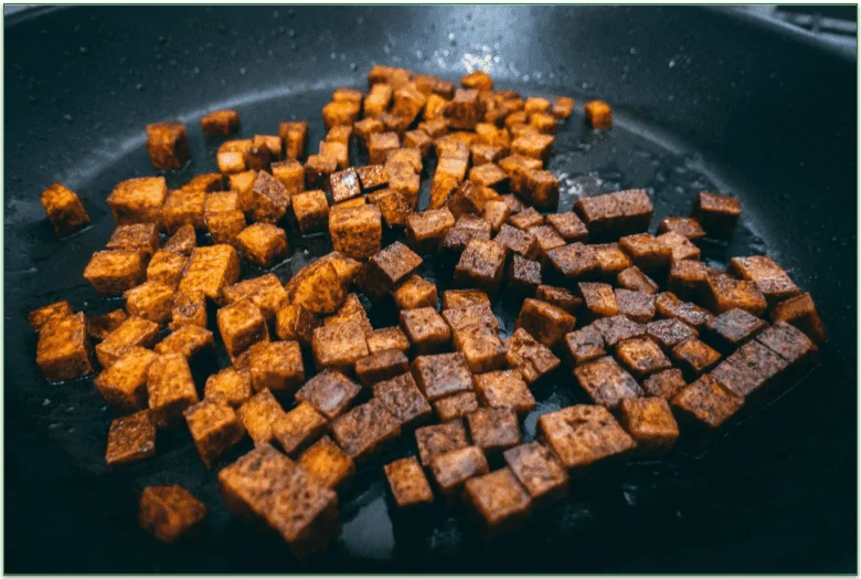 Cubes of tofu being cooked in a skillet