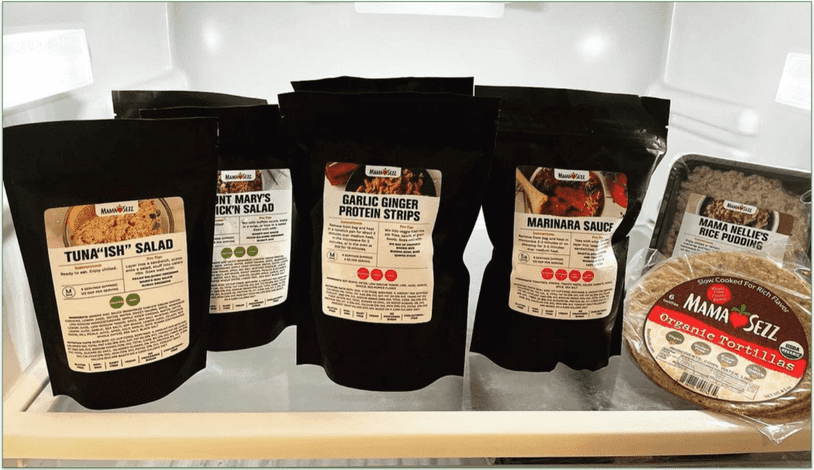 Several packaged MamaSezz food items on a refrigerator shelf