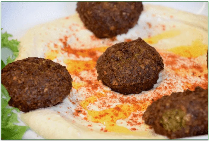 Some falafels in a bowl with hummus.