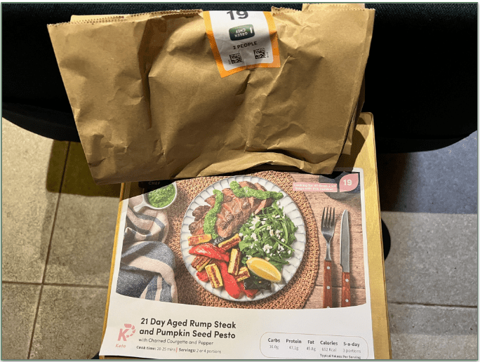 A Green Chef brown bag containing recipe ingredients along with the recipe card in front