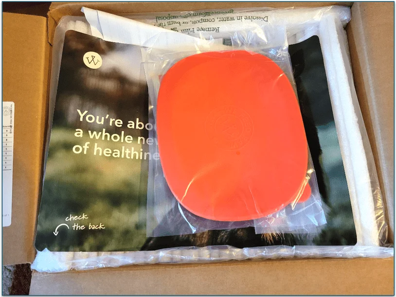 An opened WFR delivery box showing the free plastic storage container and a welcome leaflet