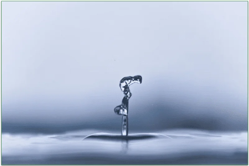 A drop of water dropping into a large body of water, such as a lake.