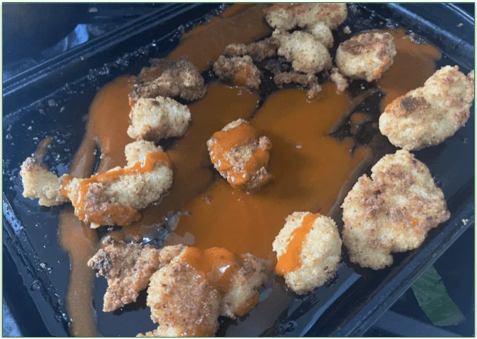 Chicken nuggets and buffalo sauce on a baking sheet