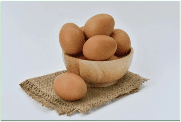 A wooden bowl of fresh brown eggs.