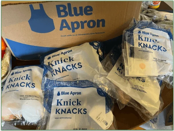 Photo of 5 plastic "Knick Knacks" containing ingredients next to a Blue Apron delivery box