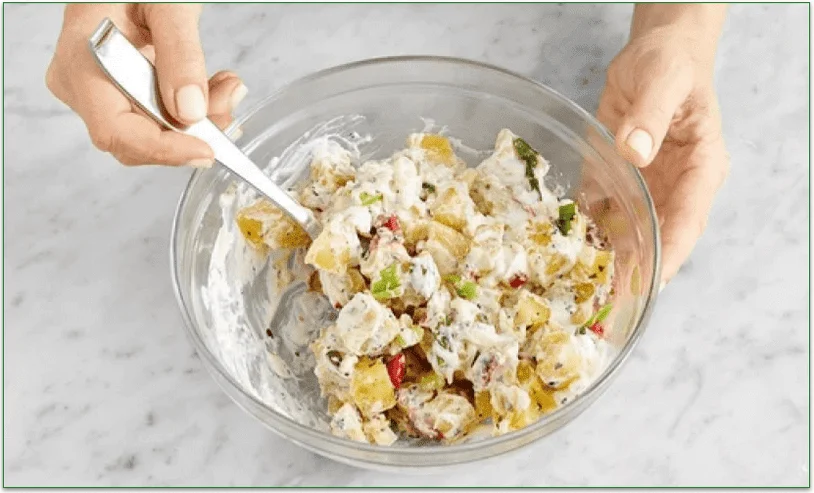 Hands mixing a bowl of potato salad from Blue Apron