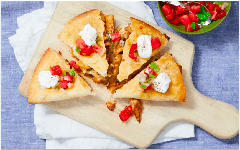 A sliced chicken quesadilla on a cutting board
