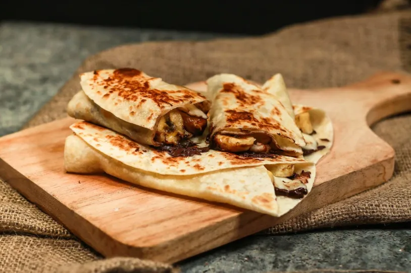 Three chocolate and banana quesadillas on a chopping board