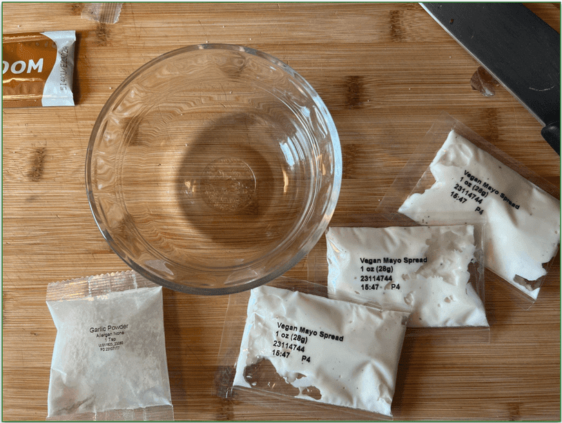 Packages of mayo garlic powder next to an empty condiment bowl