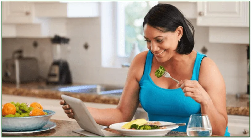 Woman looking at laptop while eating