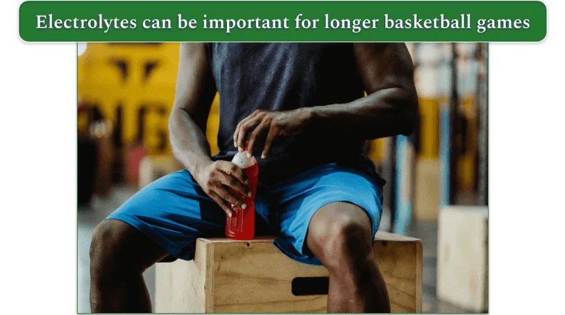 a man sitting on a wooden box with a sports drink