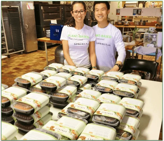 The Sprinly founders standing behind a table full of meals in the Ohio warehouse