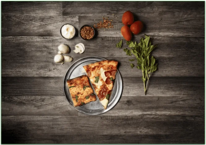 Some pizza, fruit, and veggies on a table.