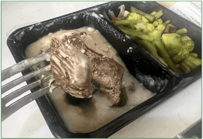 Asian Steak being eaten with a fork from the microwaveable tray