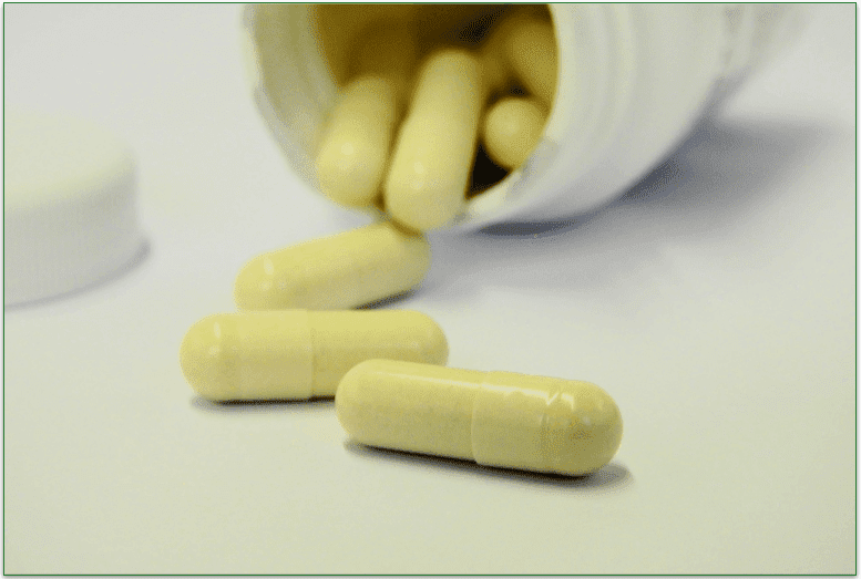 Open jar of supplement tablets spilling onto a surface