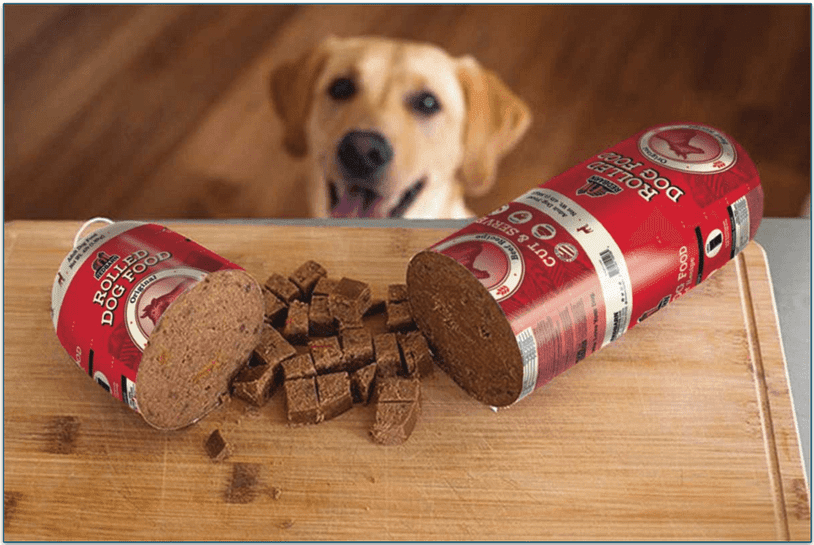 Dog looking up at a chopped rolled food meal on a board