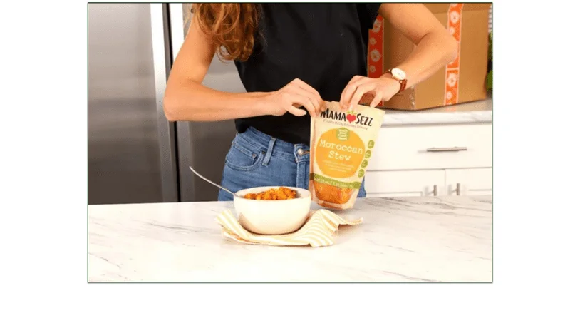 A person holding a MamaSezz packet next to a bowl of Moroccan Stew