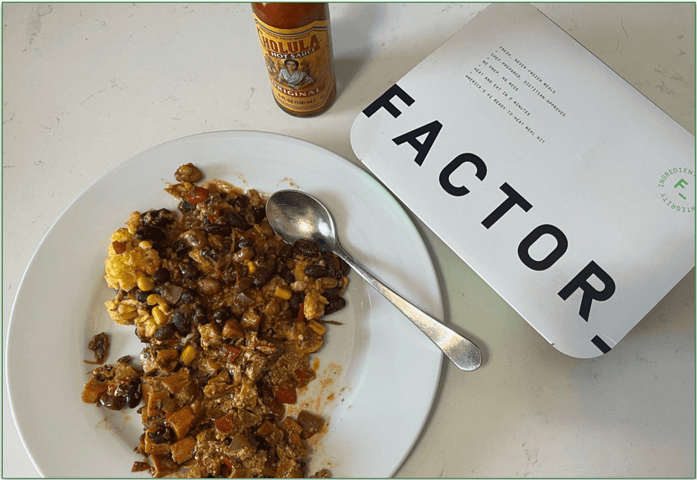 A Mexican Factor dish plated next to the white cardboard sleeve and some hot sauce