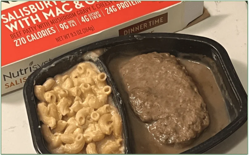 Photo of the cooked Salisbury Steak with Mac and Cheese from Nutrisystem in the microwaveable tray in front of the packaging