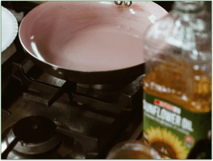 A bottle of sunflower oil next to a ceramic frying pan