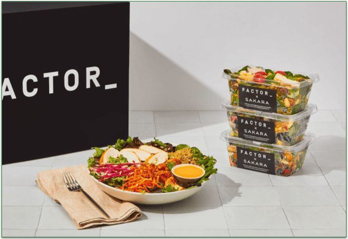 Factor salad in a bowl with three packaged salads stacked on top of each other