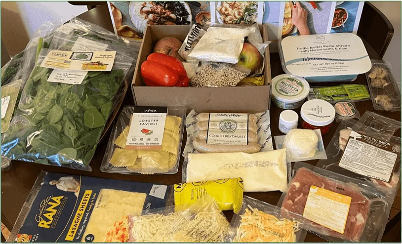Photo of the recipe cards and ingredients on a table in front of of a Marley Spoon delivery box