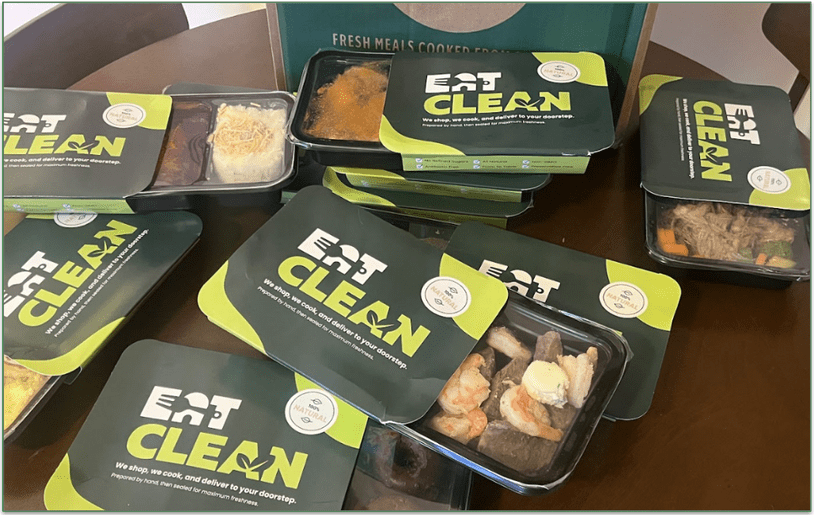 Photo of a collection of Eat Clean's prepared meals with the cardboard sleeves pushed back to reveal the contents of the trays