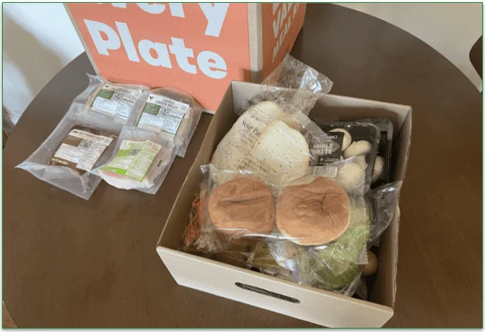 EveryPlate delivery box, packaged meats, and a cardboard tray containing all the ingredients for the recipes