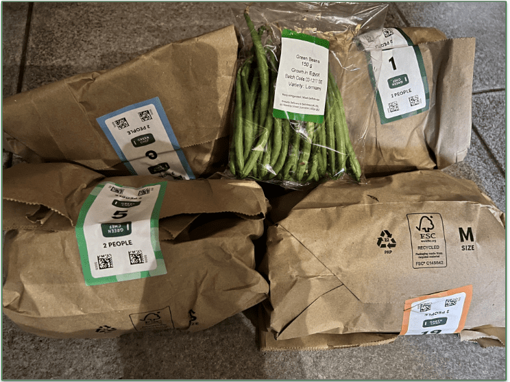 An unboxed Green Chef order showing bags stating the recipe name and number of servings
