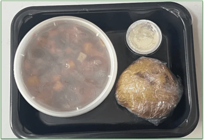 The contents of the Black Bean Chili dish with a tub of sour cream and cornbread