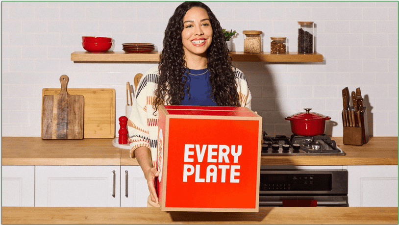 a woman holding an everyplate branded box in a kitchen