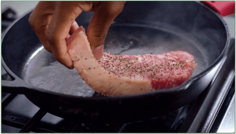 Steak being placed into a skillet