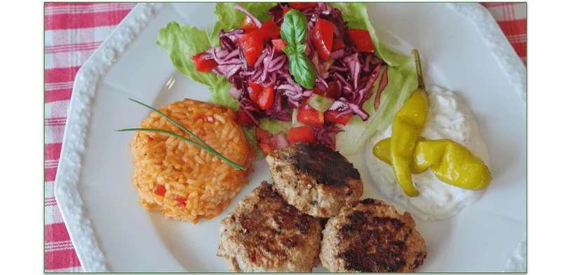 Meatballs, rice, salad, and tzatziki sauce served on a plate