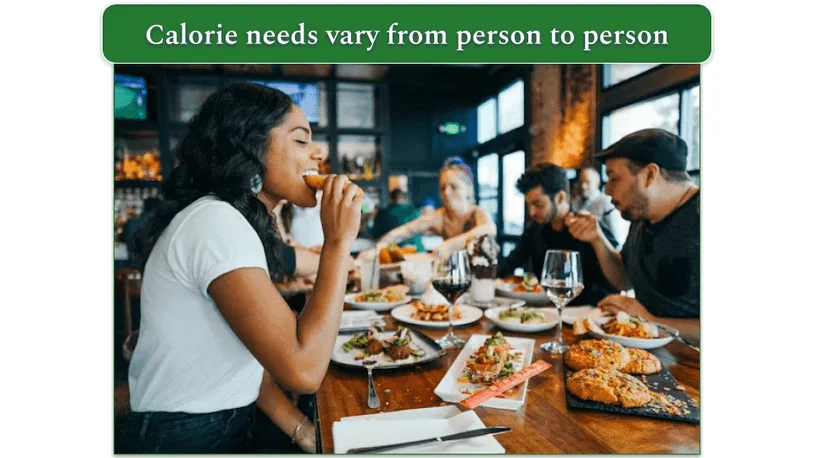 Group of people sitting round a restaurant table eating food