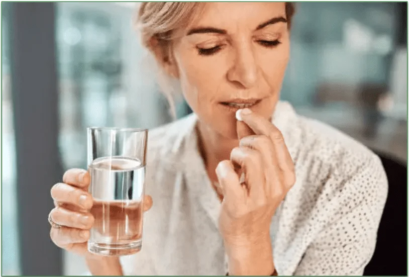 Image of a woman with a glass of water and a painkiller in hand