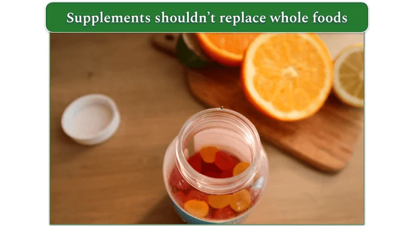 A pot of open orange gummies with a sliced orange in the background