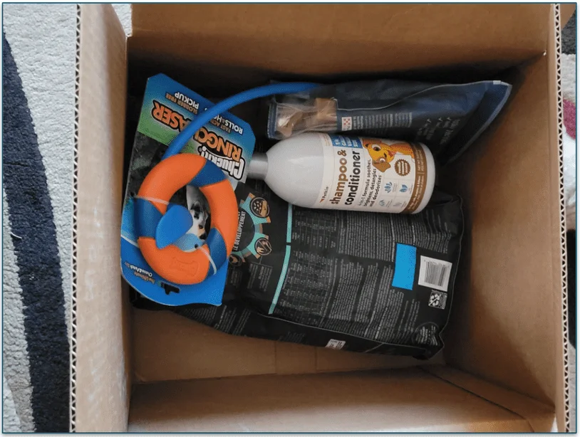 photo of an open box with 4 items from Chewy including a toy, shampoo, food, and a bag of treats