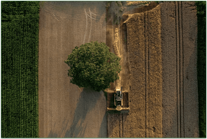 Someone using farm equipment on a farm field.