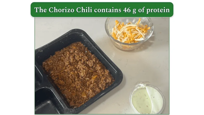 Reviewers own image of Factor Chorizo Chili with a bowl of shredded cheese and a pot of sour cream