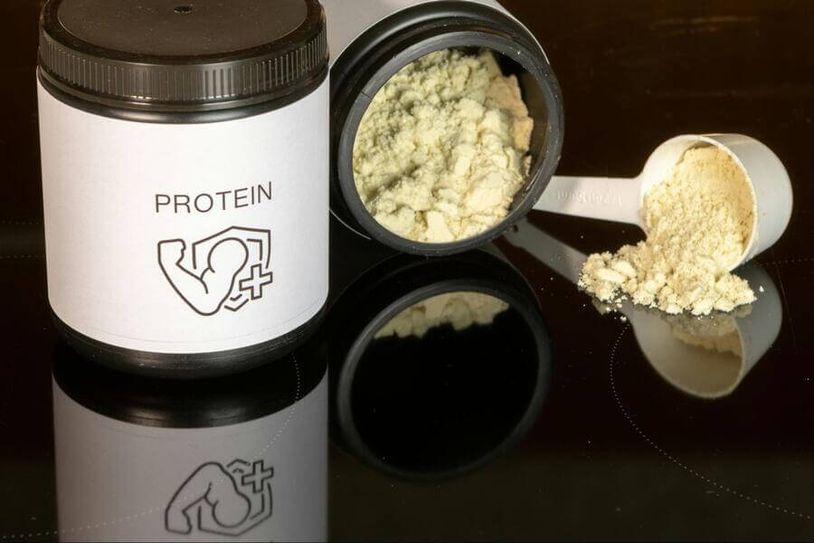 a tub of protein powder next to a scoop