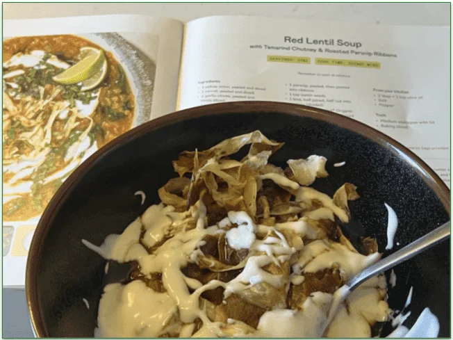 Photo of the Red Lentil Soup dish in front of the recipe in the Purple Carrot recipe booklet