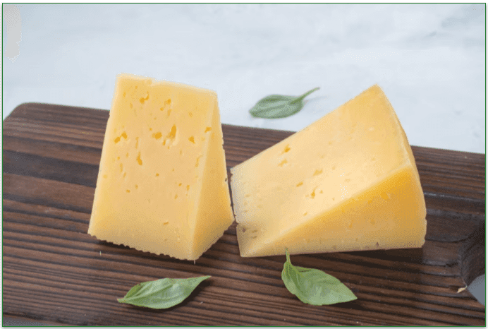 A couple of big chunks of cheese on a table.