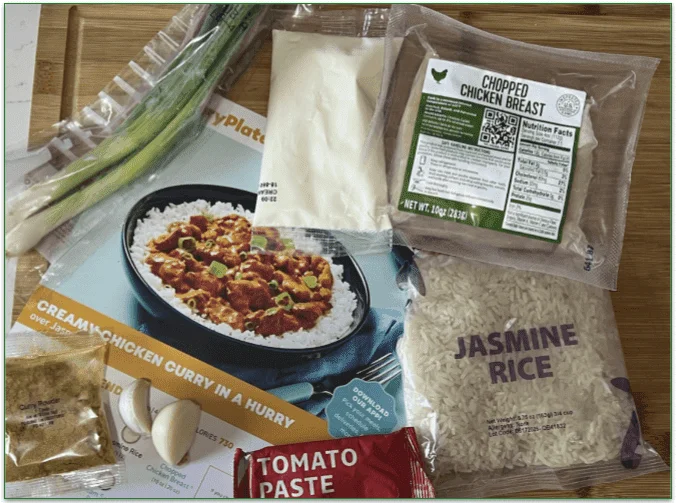 The recipe card and ingredients for the curry dish with only scallions as fresh veg