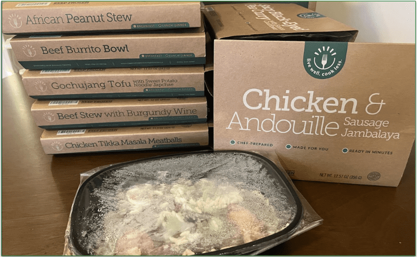 Photo of a stack of BistroMD's prepared frozen meals and one frozen meal out of the cardboard packaging in its microwaveable tray